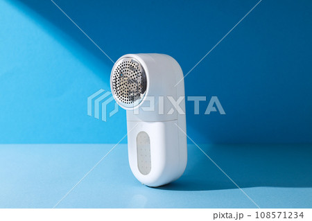 A machine for shaving fabric on clothes, on a blue background. 108571234