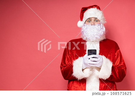 Santa Claus with a phone on a pink background. Santa Claus with a phone on a pink background. 108571625