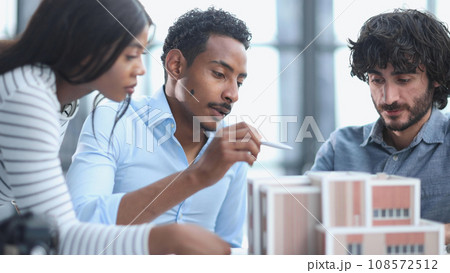 Diverse Group of Employees Smiling and Sitting Together at Conference Table Diverse Group of Employees Smiling and Sitting Together at Conference Table 108572512