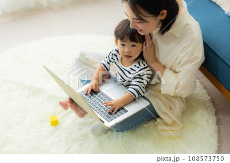 子供を抱っこしながらパソコンを見るお母さん 子供を抱っこしながらパソコンを見るお母さん 108573750