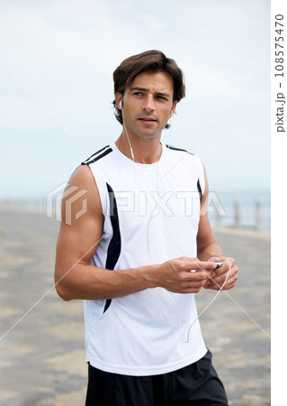 Man, fitness and earphones to listen to music, podcast and song on run, exercise and cardio. Male athlete, hearing and streaming radio, audio and sound by ocean, outdoors and inspiration for workout Man, fitness and earphones to listen to music, podcast and song on run, exercise and cardio. Male athlete, hearing and streaming radio, audio and sound by ocean, outdoors and inspiration for workout 108575470