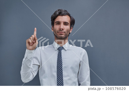 young successful man on a gray background showing fingers up young successful man on a gray background showing fingers up 108576020