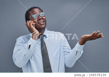 young African American man on a gray background talking on the phone young African American man on a gray background talking on the phone 108576130
