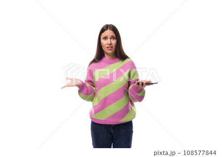 pretty upset confused young brunette woman in a striped pink blouse on a white background with copy 108577844