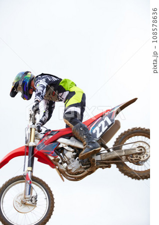Sky, fitness and man biker jumping for stunt at competition, race or training for skill. Sports, active and male athlete on a motorcycle for energy, adrenaline or adventure with speed in nature. Sky, fitness and man biker jumping for stunt at competition, race or training for skill. Sports, active and male athlete on a motorcycle for energy, adrenaline or adventure with speed in nature. 108578636