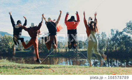 Friends, jump and camping are happy on adventure with water for fun in nature on weekend. Travel, group and freedom at campsite on holiday with hug at park with lake in environment for vacation. 108578789