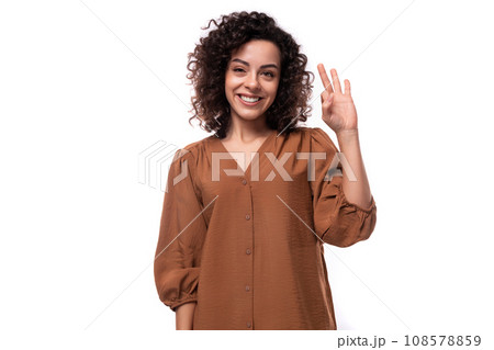 young successful pretty caucasian woman with curly black hair is dressed in a brown shirt on a white young successful pretty caucasian woman with curly black hair is dressed in a brown shirt on a white 108578859