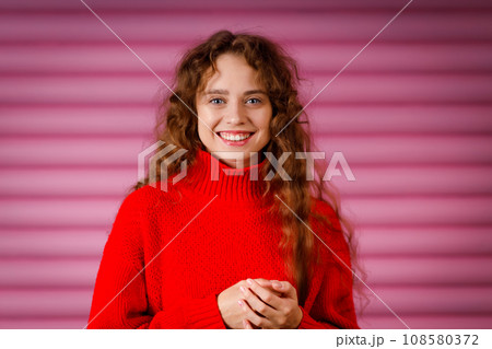 Happy smiling young adult woman wearing winter warm red sweater indoors looking at camera with joyful smile Happy smiling young adult woman wearing winter warm red sweater indoors looking at camera with joyful smile 108580372