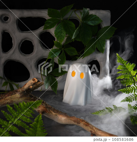 White ghost with yellow eyes in ivy and fern leaves. Selective focus. 108581686