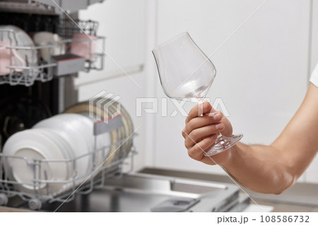 male hand takes wine glasses out of dishwasher in kitchen. 108586732