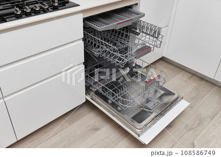 Modern built-in empty dishwasher with open door in the kitchen . 108586749