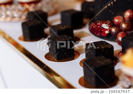 French mousse cake covered with dark chocolate icing. Modern European dessert decorated with gold. selective focus French mousse cake covered with dark chocolate icing. Modern European dessert decorated with gold. selective focus 108587437
