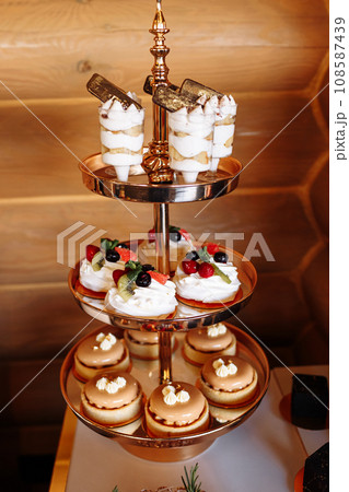 luxury wedding catering, table with modern desserts, cupcakes, sweets with fruits. delicious candy bar at expensive wedding reception. party holiday celebration. selective focus luxury wedding catering, table with modern desserts, cupcakes, sweets with fruits. delicious candy bar at expensive wedding reception. party holiday celebration. selective focus 108587439