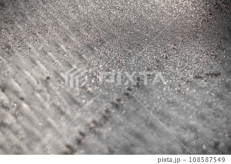 Ice and frost background on frozen glass. Colored in silver or grey tone. Selective focus at center with blur edges of image 108587549