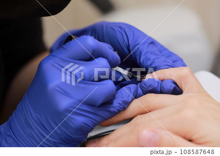 Closeup shot of manicure in a beauty salon. Master during a manicure. Master manicurist varnishes the gel on the nails of a female client. The concept of beauty and health. 108587648