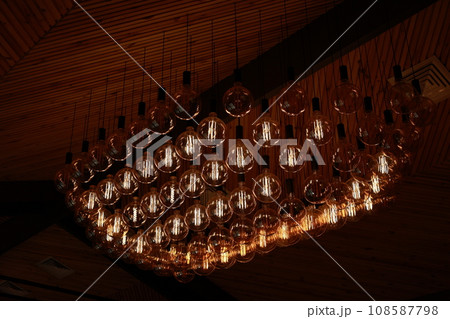 Stylish, modern and decorative lamps of Edison of round shape in the rows. Light bulbs in retro style. A lot celling glowing vintage LED lamps. Object for interior decoration, selective focus photo 108587798