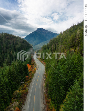 Scenic Highway by Trees with Mountains in Background. Colorful Cloudy Sky. Scenic Highway by Trees with Mountains in Background. Colorful Cloudy Sky. 108588230