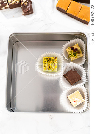 Packaging a homemade variety of fudge for Christmas food gifts into tin boxes. Packaging a homemade variety of fudge for Christmas food gifts into tin boxes. 108592022