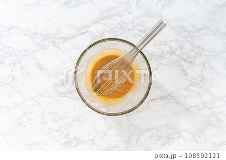 Flat lay. Mixing wet ingredients in a large glass mixing bowl to bake lemon poppy seed muffins. 108592121
