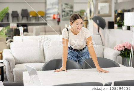 Girl buyer choose dining table desk in furniture store showroom 108594553