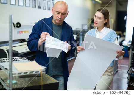 Man and woman printing office workers discussing job Man and woman printing office workers discussing job 108594700