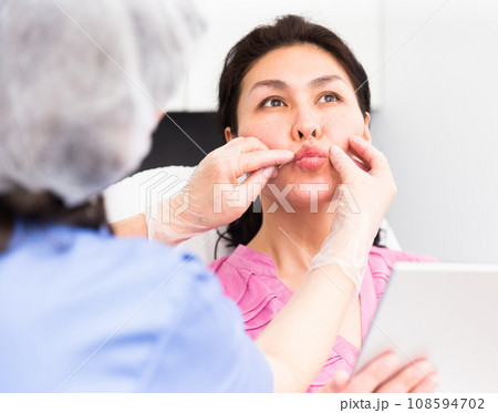 Doctor beautician discussing with woman cosmetological procedure Doctor beautician discussing with woman cosmetological procedure 108594702