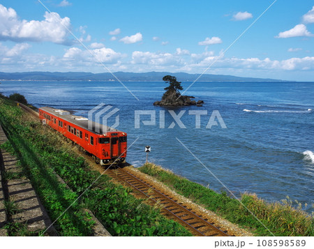 初秋の雨晴海岸　展望広場から富山湾岸を走るキハ40系気動車と女岩を臨む 108598589
