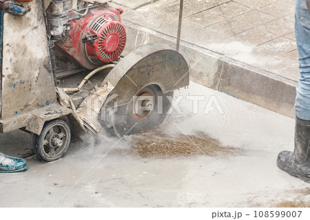 Worker using diamond saw blade machine cutting concrete road at construction site Worker using diamond saw blade machine cutting concrete road at construction site 108599007