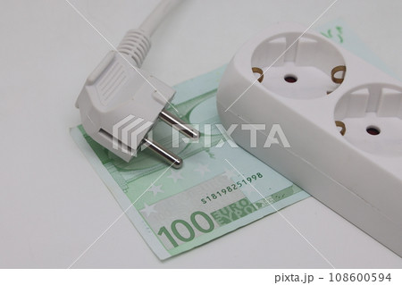White electric cable and extension cord socket lie on a banknote, expensive electricity 108600594