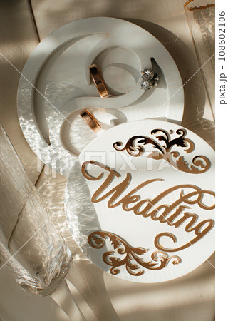 Wedding rings on a wooden box with shadows of leaves Wedding rings on a wooden box with shadows of leaves 108602106