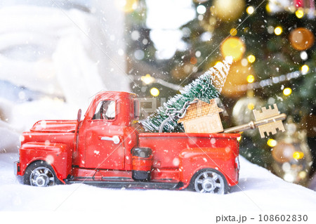 Red retro car with a Christmas tree decorates with the house key in the pickup truck for Christmas. Buying a home, moving, mortgage, loan, real estate, festive mood, New Year 108602830