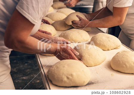 Bakers forming bread dough in a bakery Bakers forming bread dough in a bakery 108602928