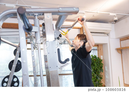 スポーツジムの懸垂マシンで筋トレする男性 108603816