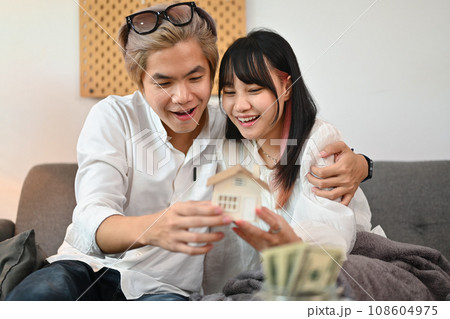 Happy young couple with small house model. Financial planning and real estate purchase concept Happy young couple with small house model. Financial planning and real estate purchase concept 108604975