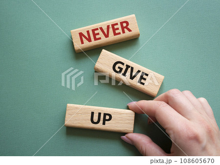 Never give up symbol. Concept words Never give up on wooden blocks. Beautiful grey green background. Businessman hand. Business and Never give up concept. Copy space. 108605670