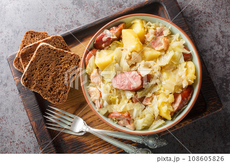 Cabbage stewed with potatoes, sausage, bacon and onions close-up in a bowl. Horizontal top view 108605826