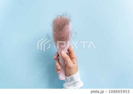 Hair loss concept - female hand holding brush with lost hair Hair loss concept - female hand holding brush with lost hair 108605953