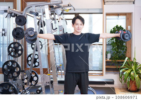 スポーツジムでダンベルで筋トレする男性（サイドレイズ） 108606971