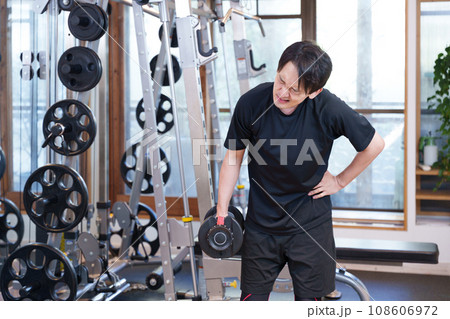スポーツジムでダンベルで筋トレする疲れた男性 108606972