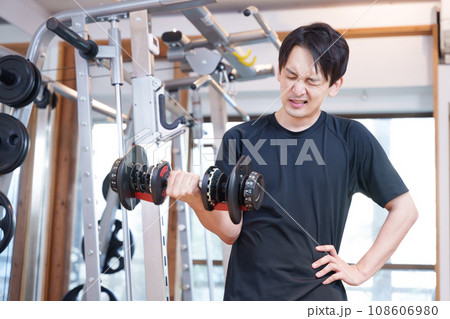 スポーツジムでダンベルで筋トレする疲れた男性 108606980