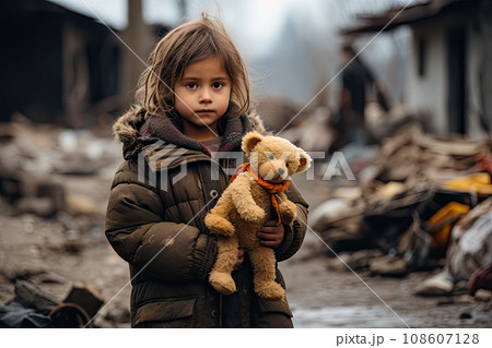 a little girl holding a teddy bear in front of the rubble - covered area that has been destroyed by fire a little girl holding a teddy bear in front of the rubble - covered area that has been destroyed by fire 108607128