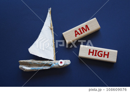 Aim High symbol. Wooden blocks with words Aim High. Beautiful orange background with boat. Business and Aim High concept. Copy space. 108609076