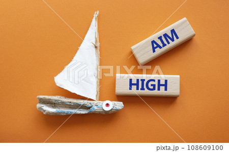 Aim High symbol. Wooden blocks with words Aim High. Beautiful orange background with boat. Business and Aim High concept. Copy space. 108609100