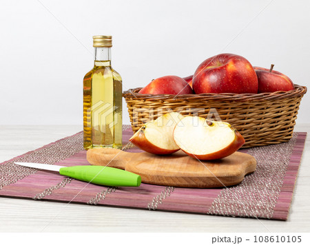 Red apples in a basket and cider vinegar in a glass bottle on the table. Red apples in a basket and cider vinegar in a glass bottle on the table. 108610105