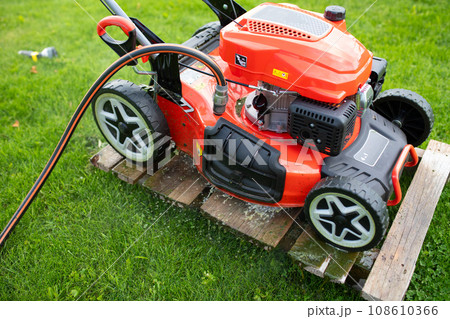 petrol self-propelled lawn mower on green grass with water connection 108610366
