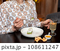 Cropped view of woman holding vegetarian dessert souffle and teacup 108611247