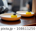 Yellow cheesecake dessert in white plate with black chocolate.  108611250