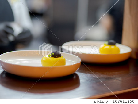 Yellow cheesecake dessert in white plate with black chocolate. Yellow cheesecake dessert in white plate with black chocolate. 108611250