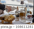 Sommelier pouring white wine into glasses with hidden bottle 108611281
