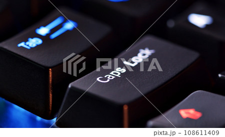 Keyboard key  - Caps lock - macro shot.  Modern gaming keyboard close-up with beautiful color backlight.  Macro shooting of the rgb computer keyboard with backlight.  Low angle view with soft focus. 108611409